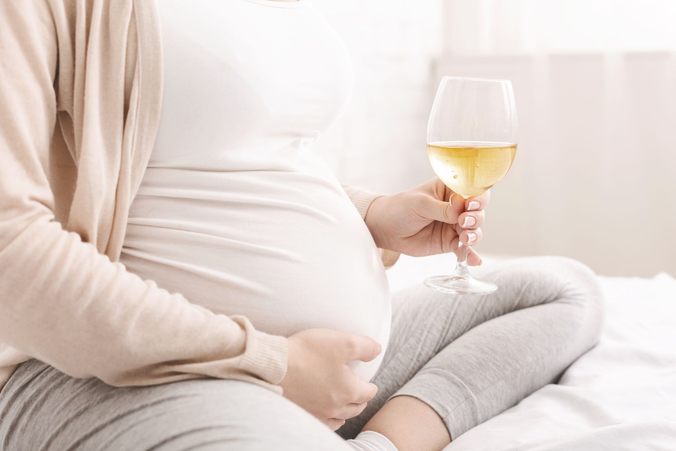 pregnant woman in kitchen with glass of red wine s WPZG9AB
